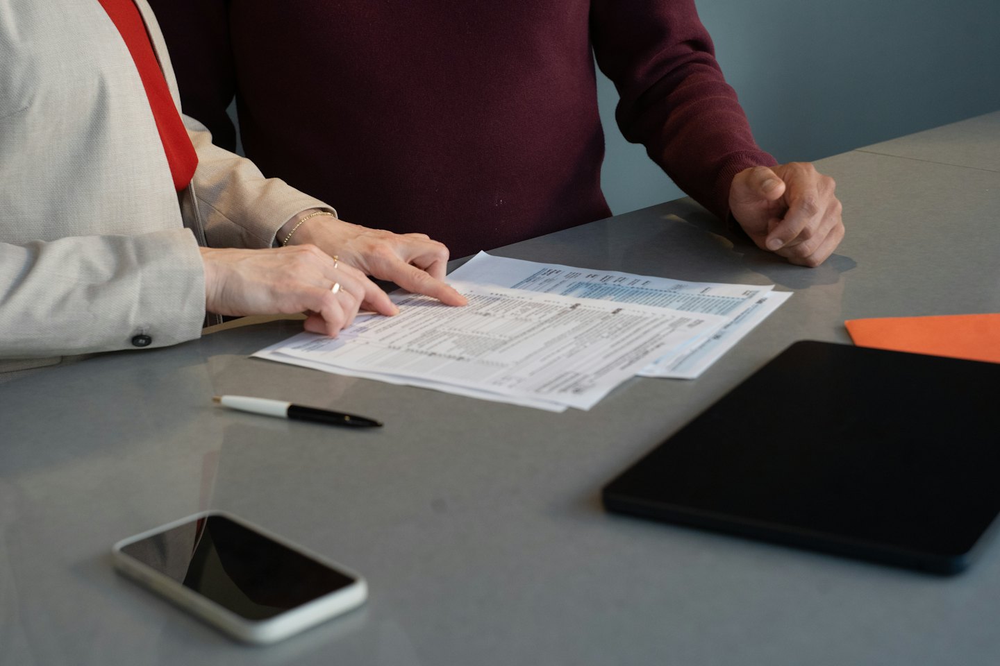 Due persone esaminano documenti finanziari a una scrivania.